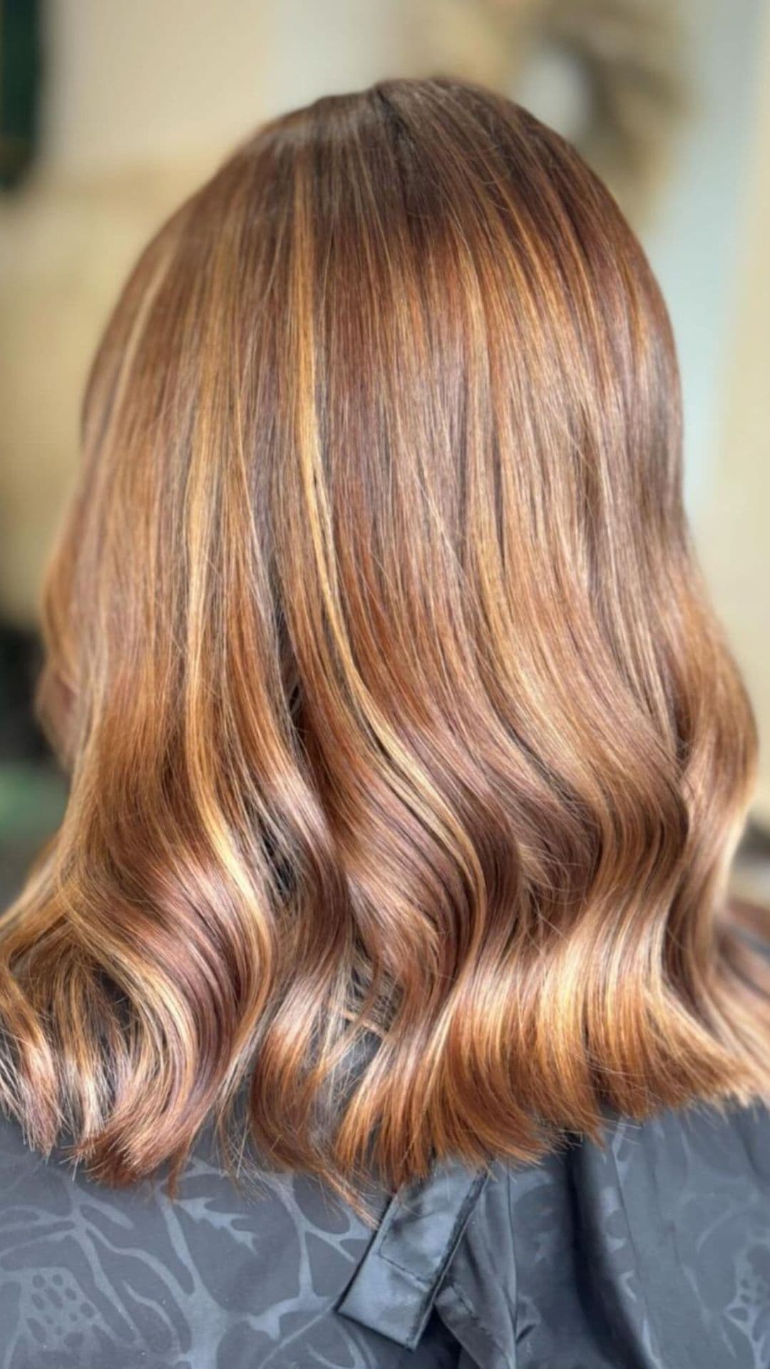 A woman modelling a chestnut balayage on light golden brown hair color.