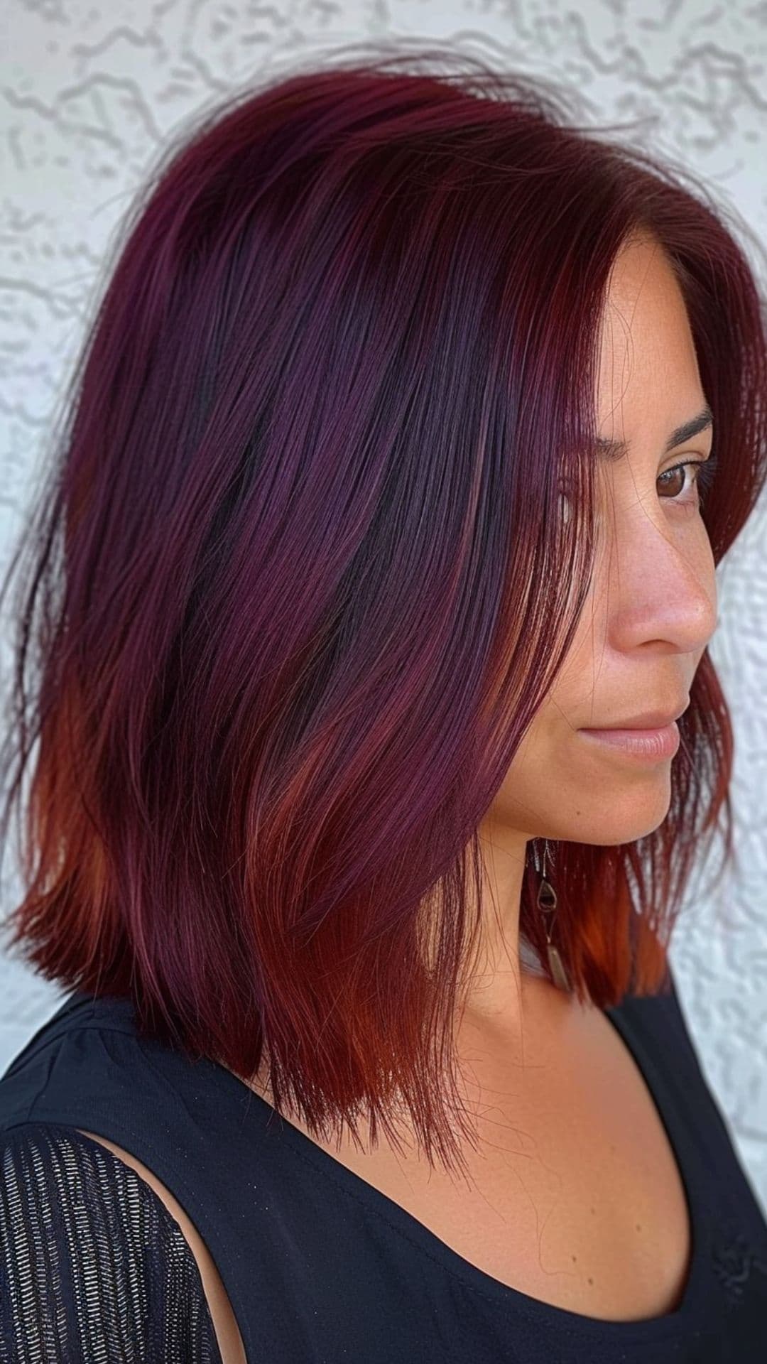 Una mujer modelando un cabello color burdeos intenso.