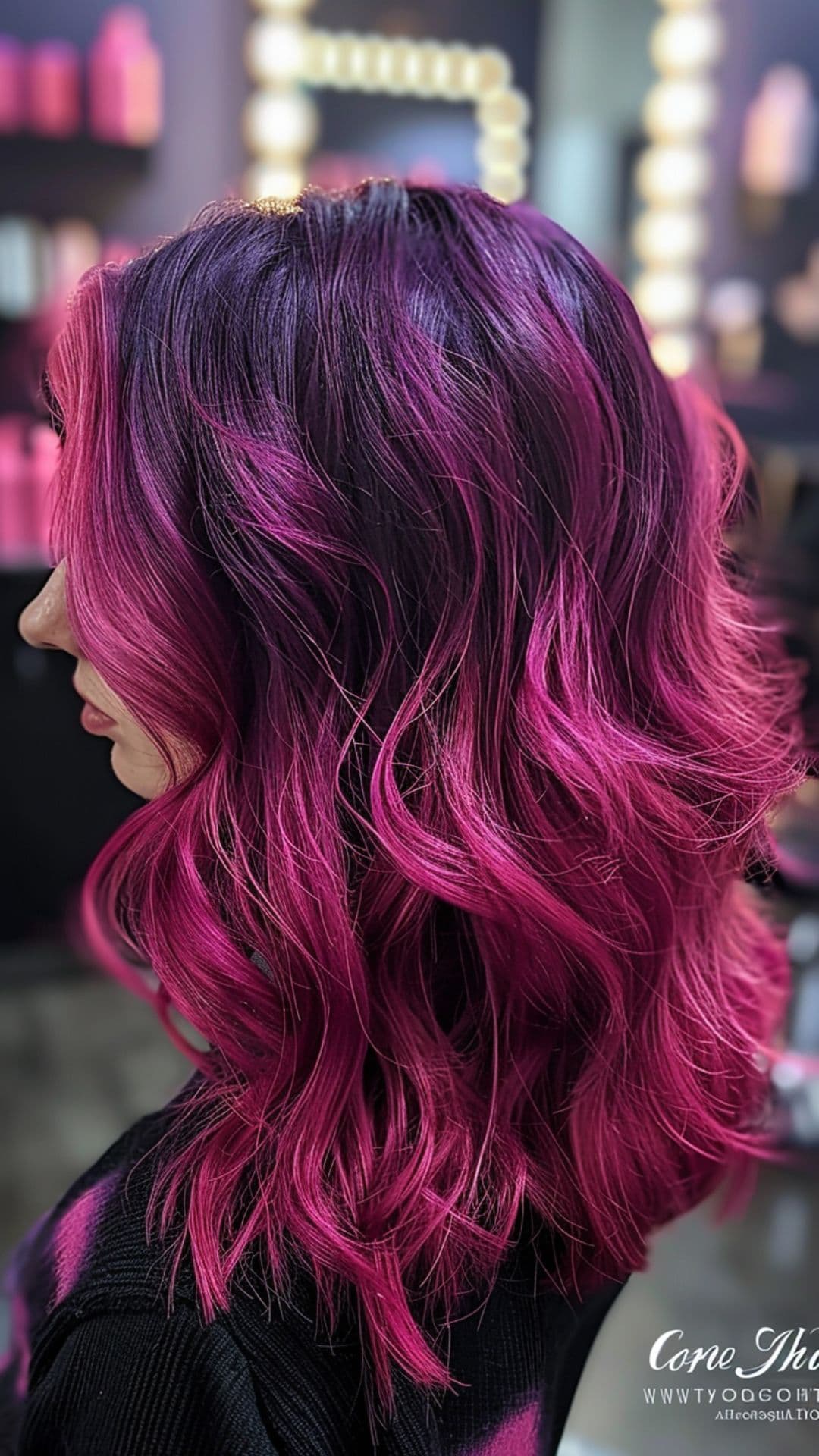 A woman modelling a deep purple root into a bright magenta hair.