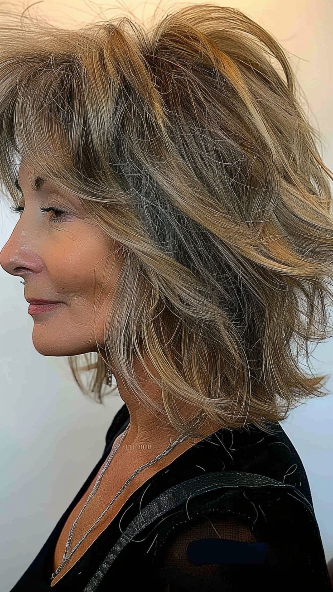An older woman modelling a feathered bangs with wavy lob.