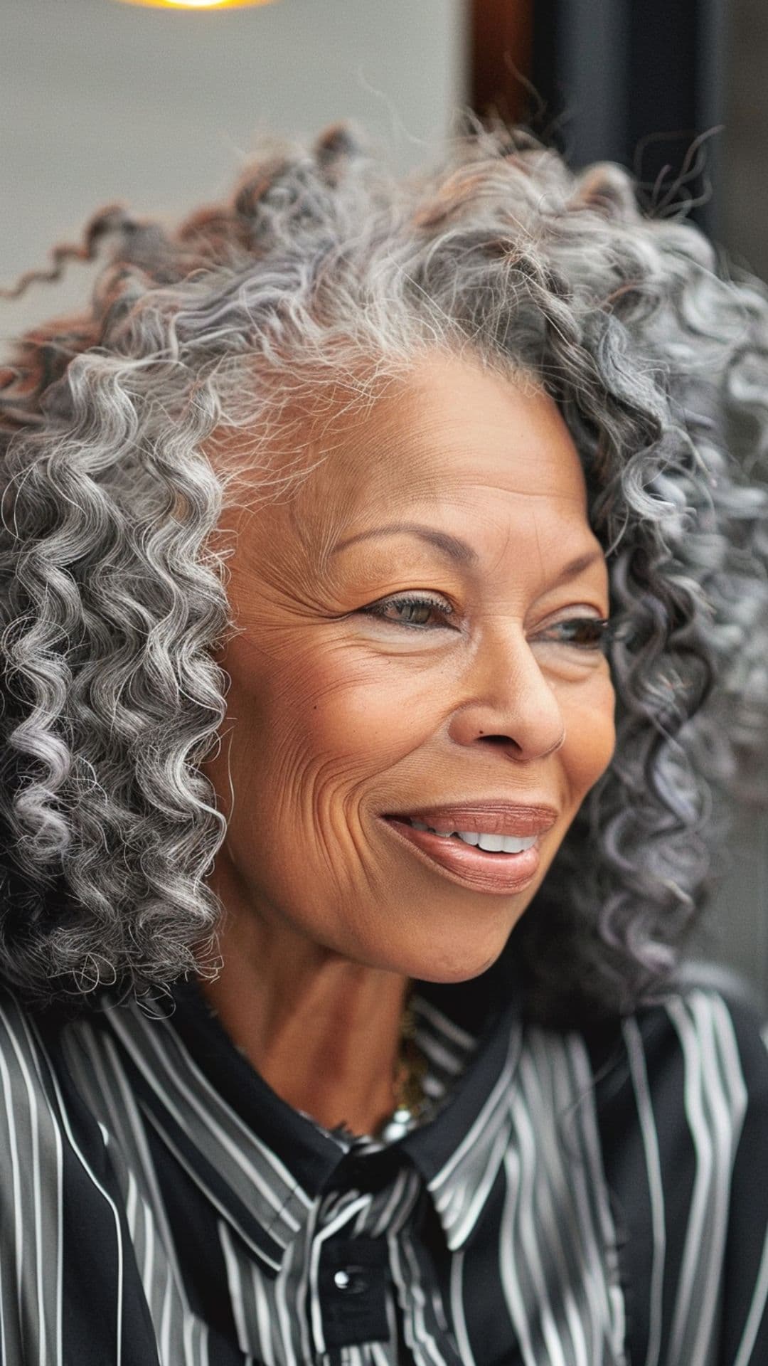 An older black woman modelling a salt and pepper afro hairstyle.