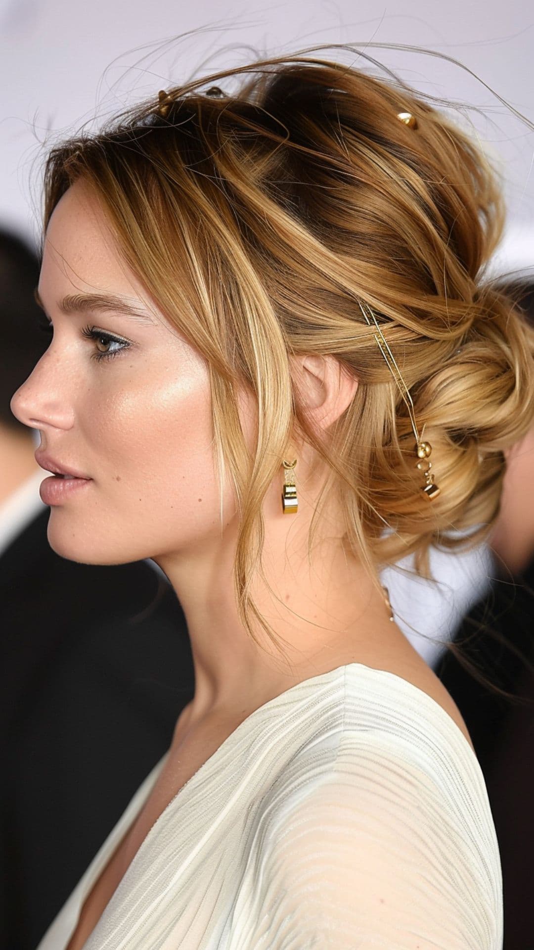 A woman modelling Jennifer Lawrence's messy updo with face-framing layers.