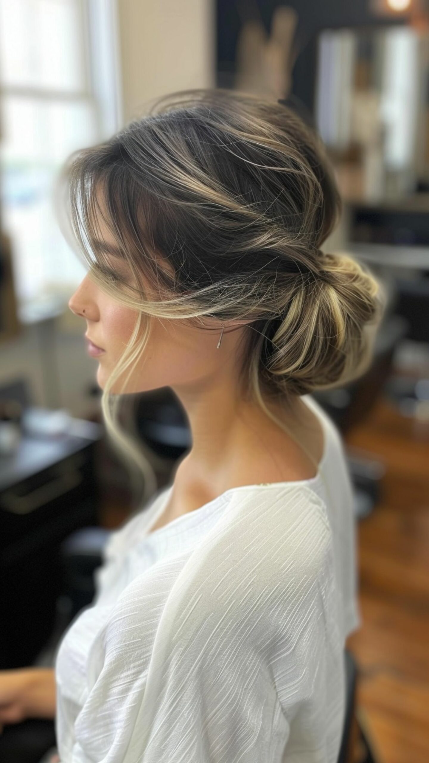 A woman modelling a low chignon with side swept bangs hairstyle.