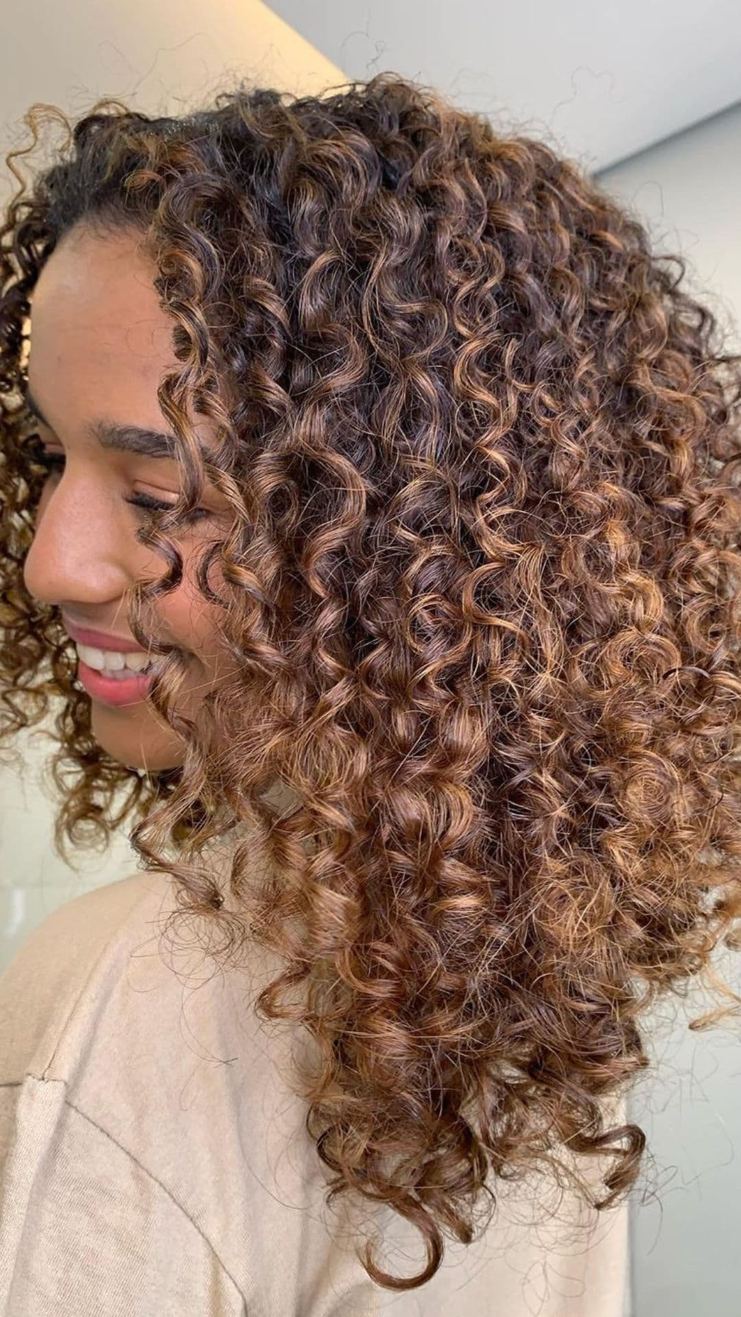 A woman modelling a natural curls with light brown accents.