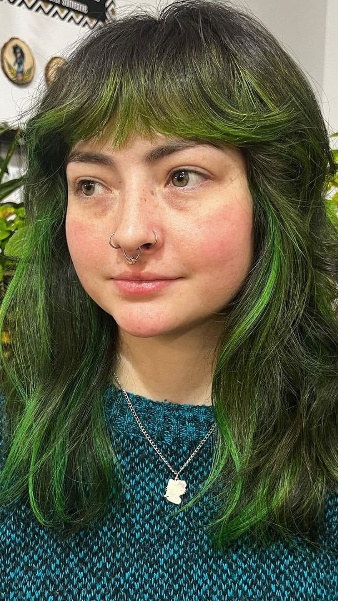 A woman modelling a green shag with brow-length bangs hairstyle.