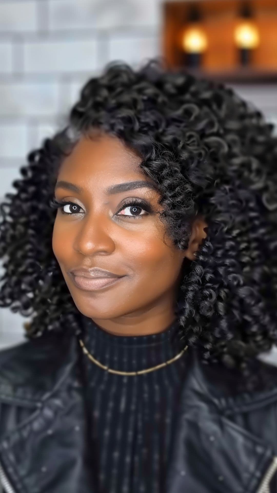 A black woman modelling a shoulder-length twist out hairstyle.