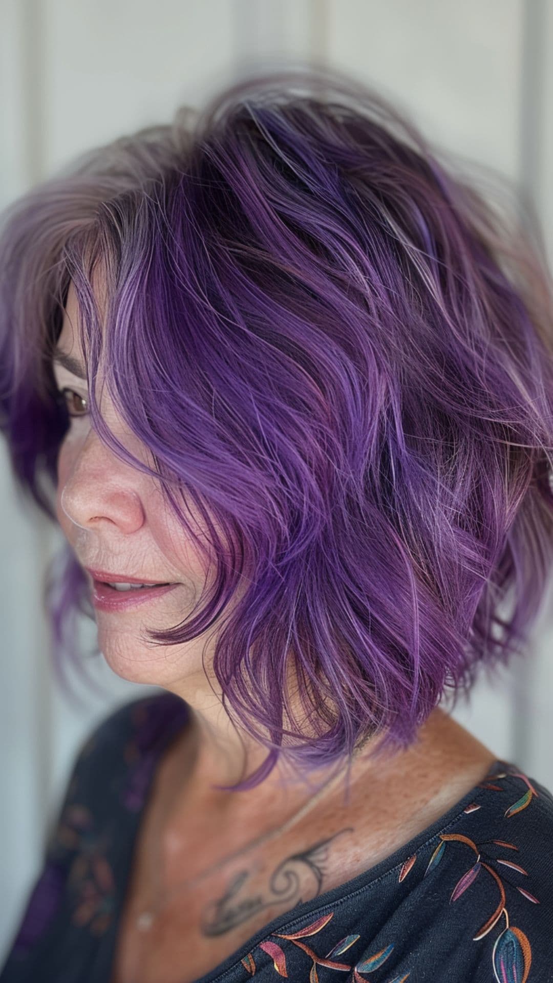 An old woman modelling an a-line choppy shaggy bob with purple hair color.