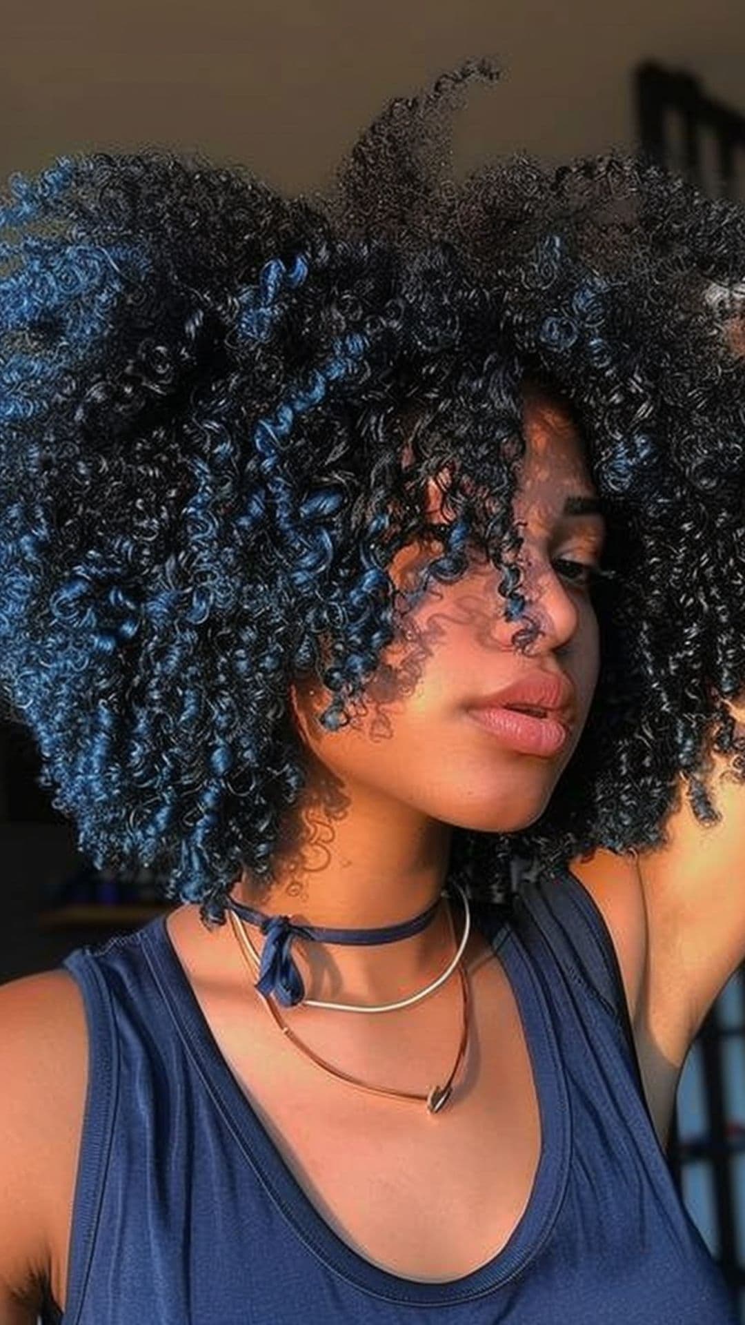 A woman modelling a blue black curly hair.