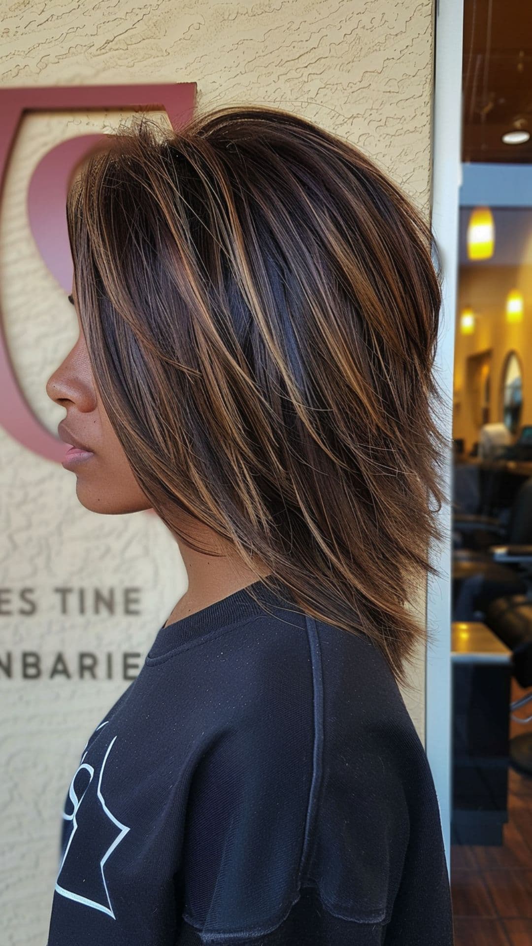 A woman with dark skin tone modelling a caramel hair highlights.