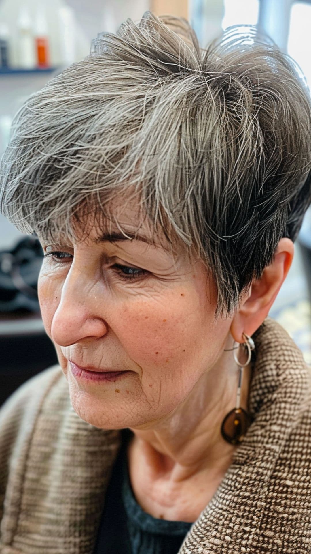 An old woman modelling a choppy pixie with long bangs.