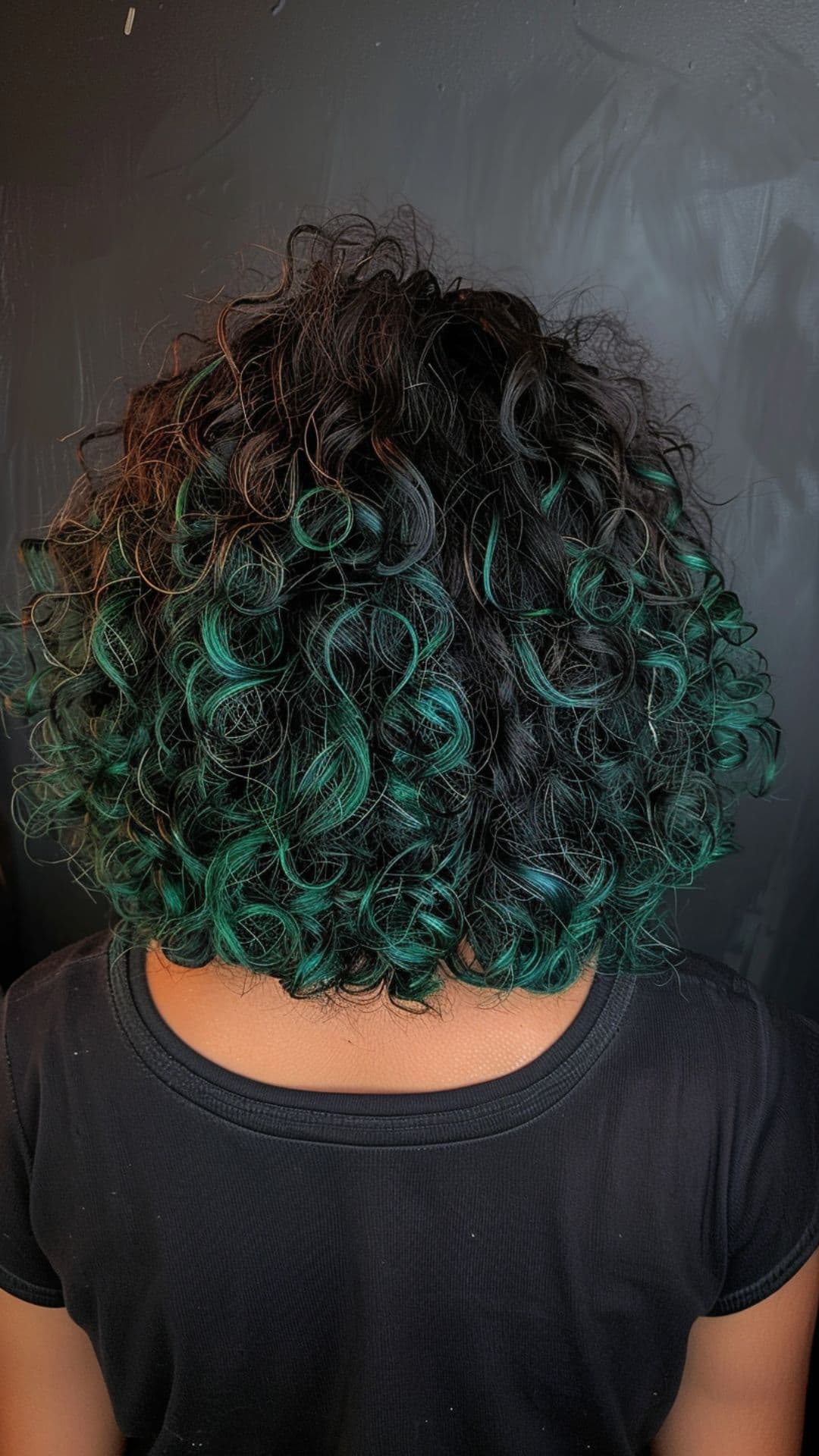 A woman modelling a curly hair with green highlights.
