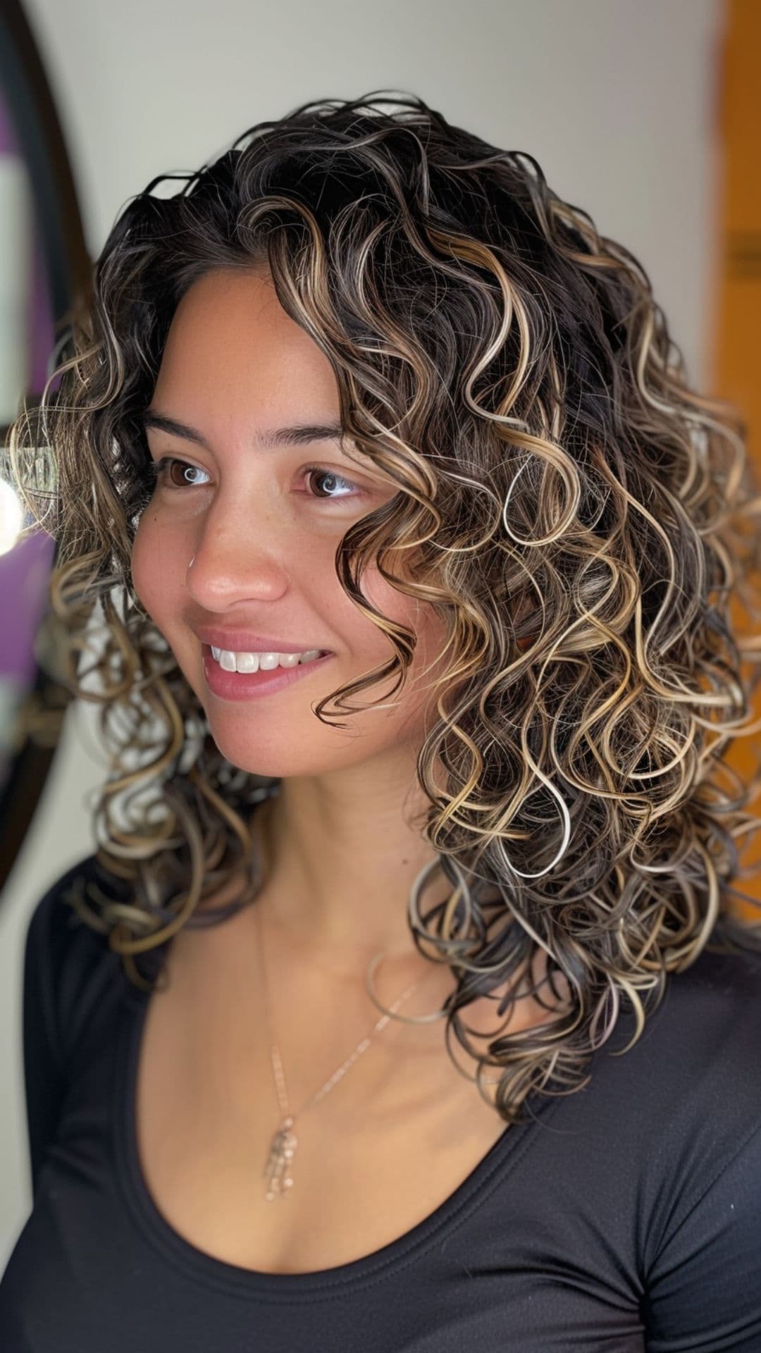 A woman modelling a honey blonde highlights on curly hair.