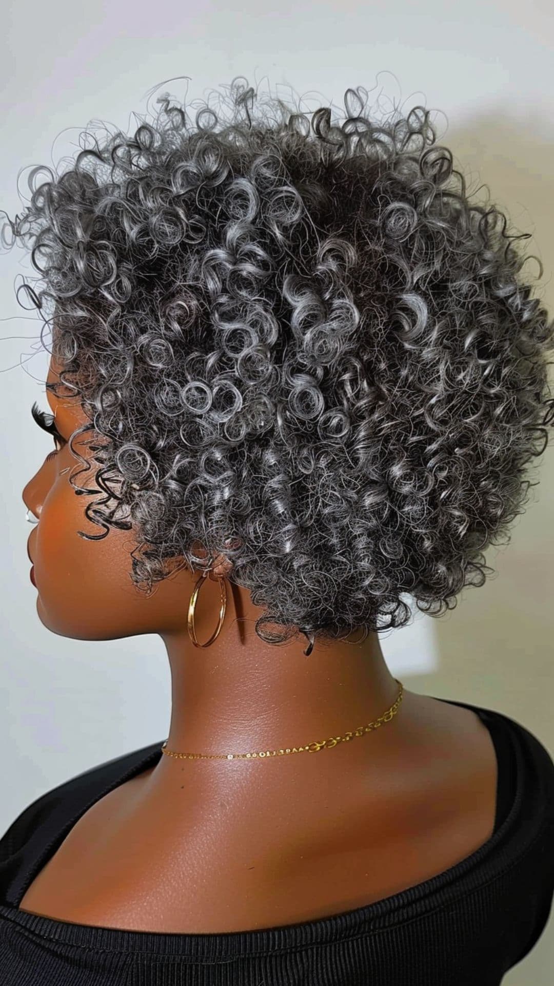A black woman modelling a curly silver grey hair.