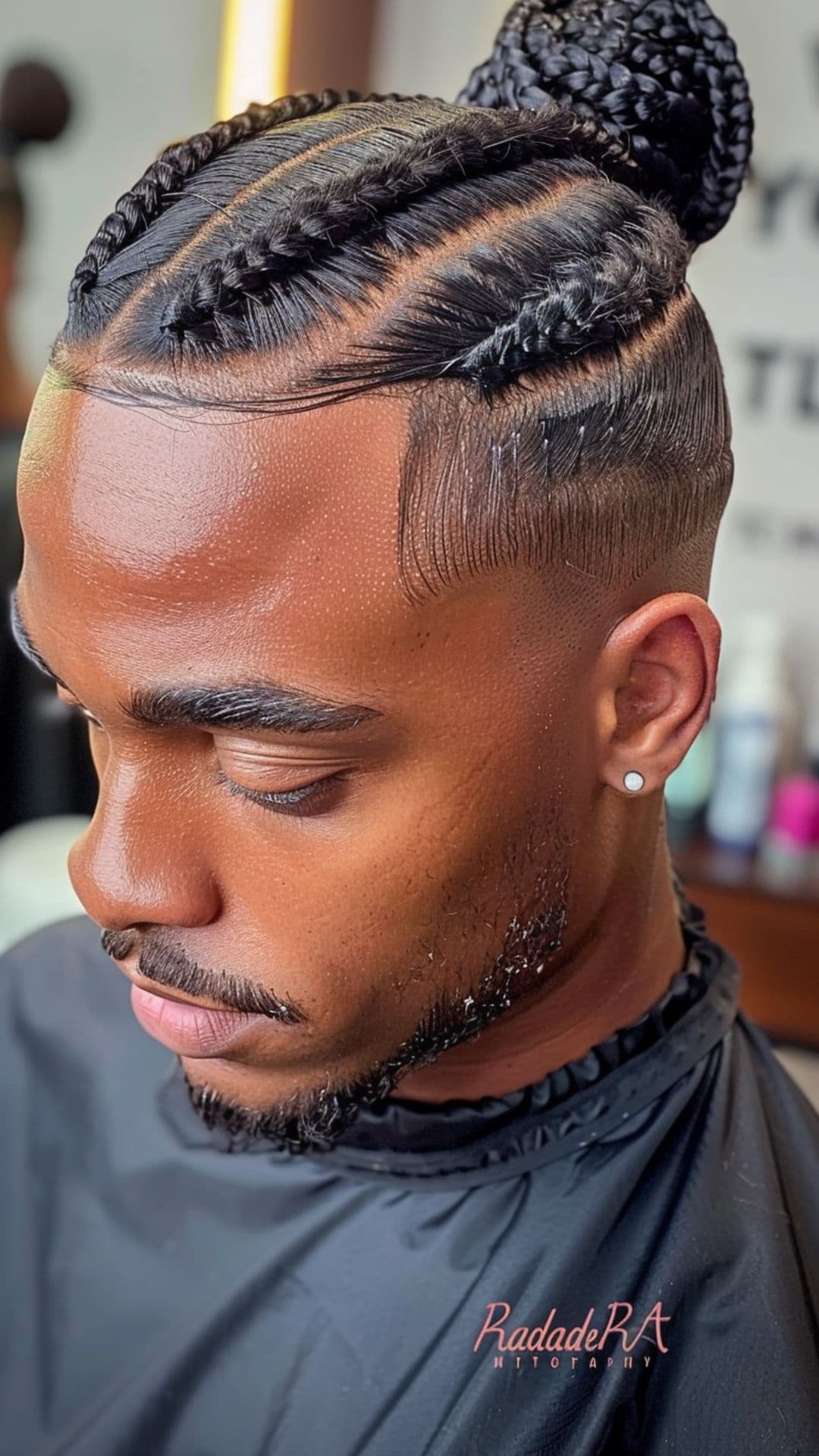 A black man modelling a braided bun hairstyle.