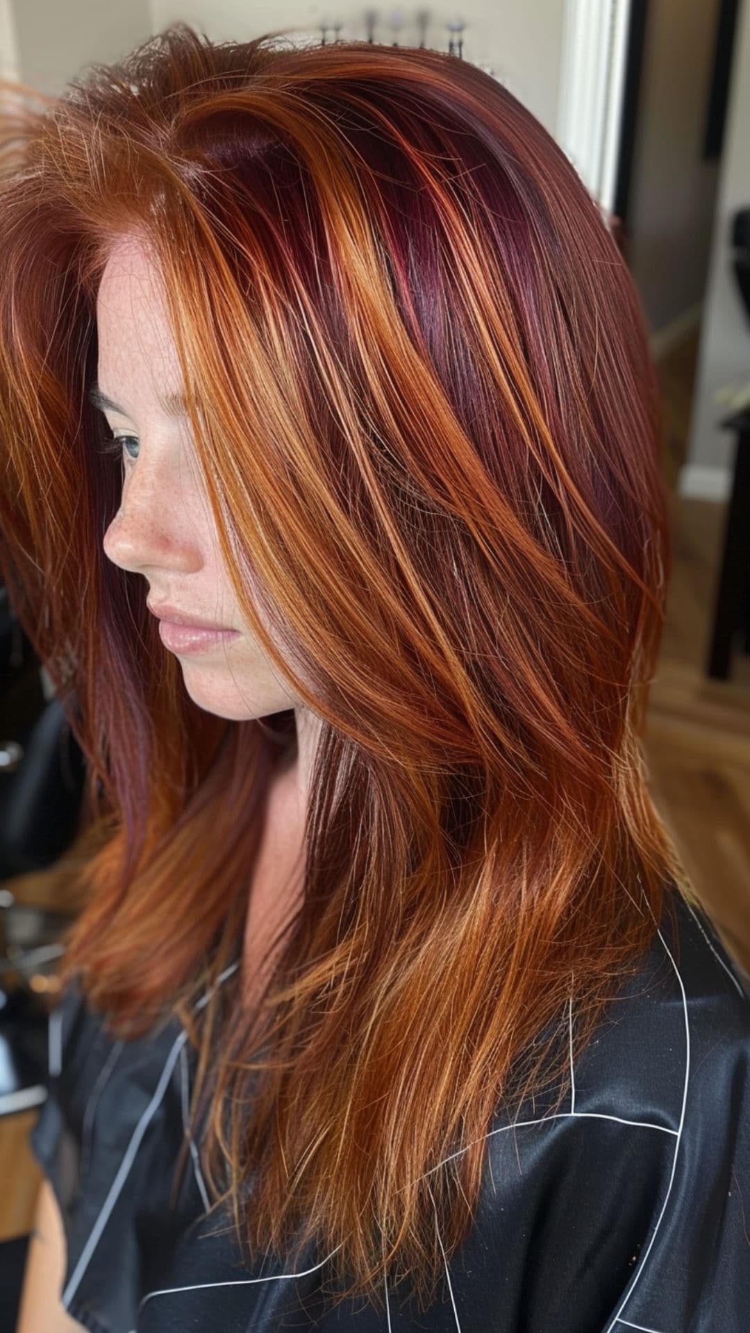 Uma mulher modelando mechas grossas de cobre em um cabelo ruivo violeta.