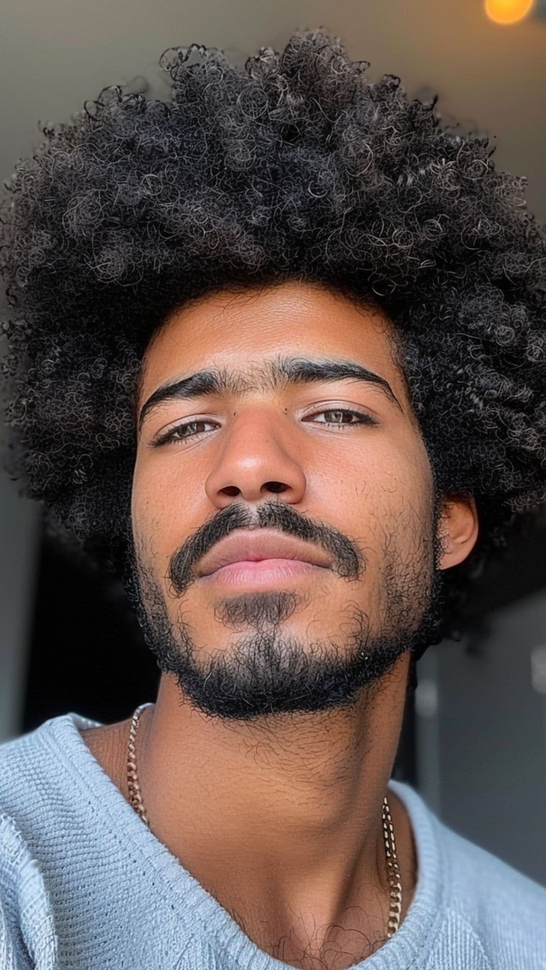 A black man modelling a curly Afro hairstyle.