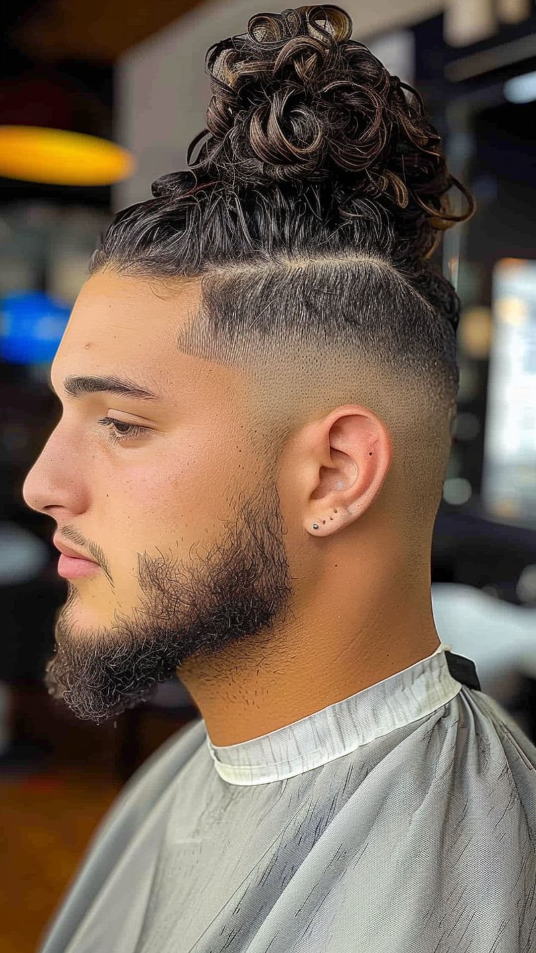 A man modelling a curly man bun hairstyle.
