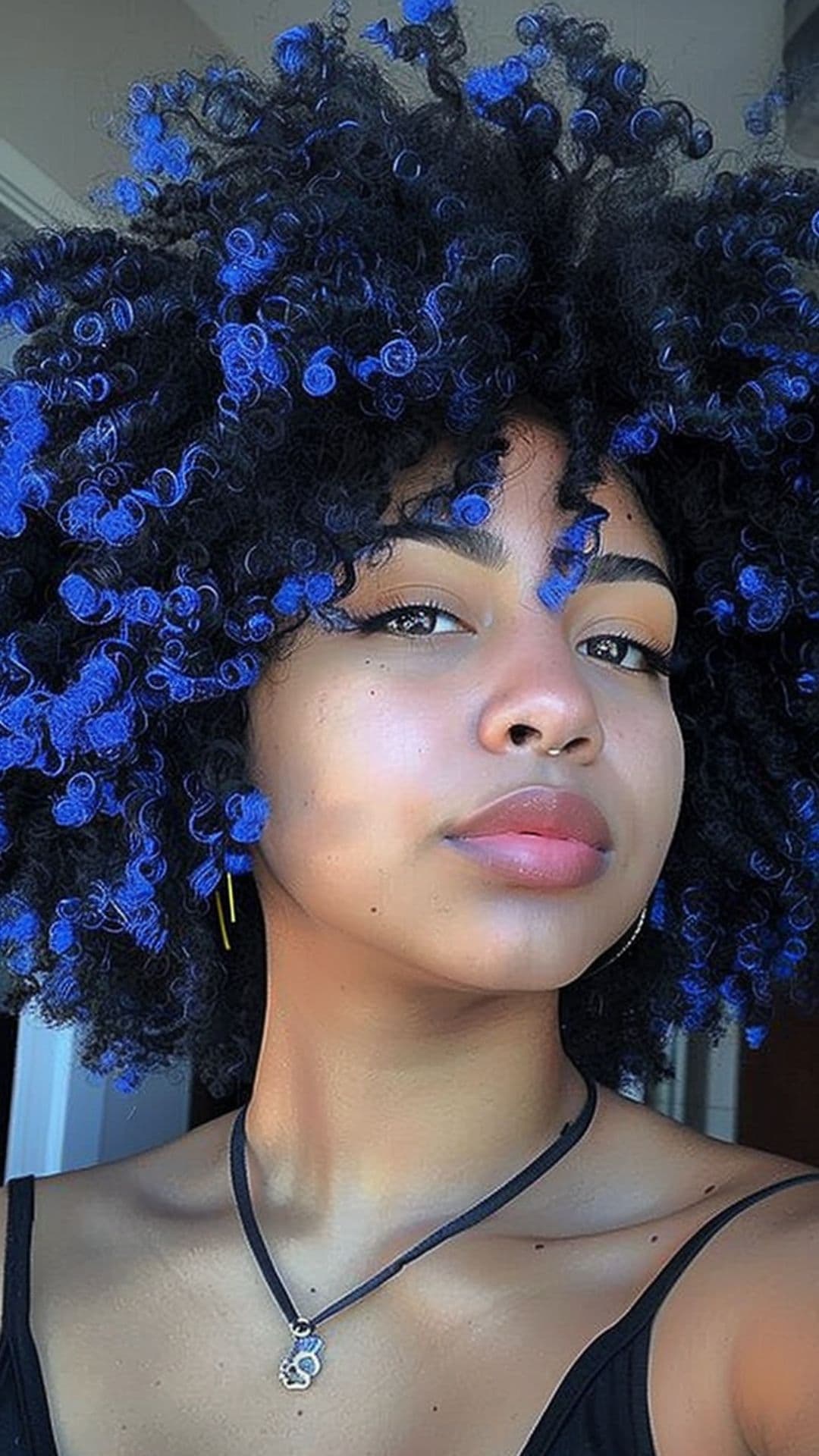 A black woman modelling an electric blue tips on afro hair.