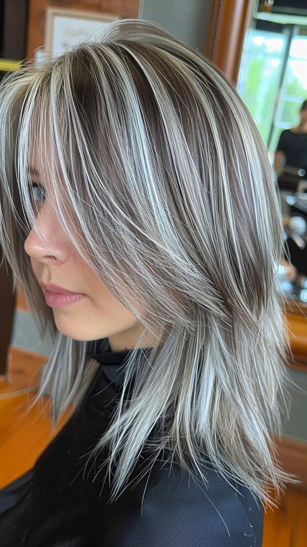 Uma mulher modelando um cabelo com mechas prateadas.