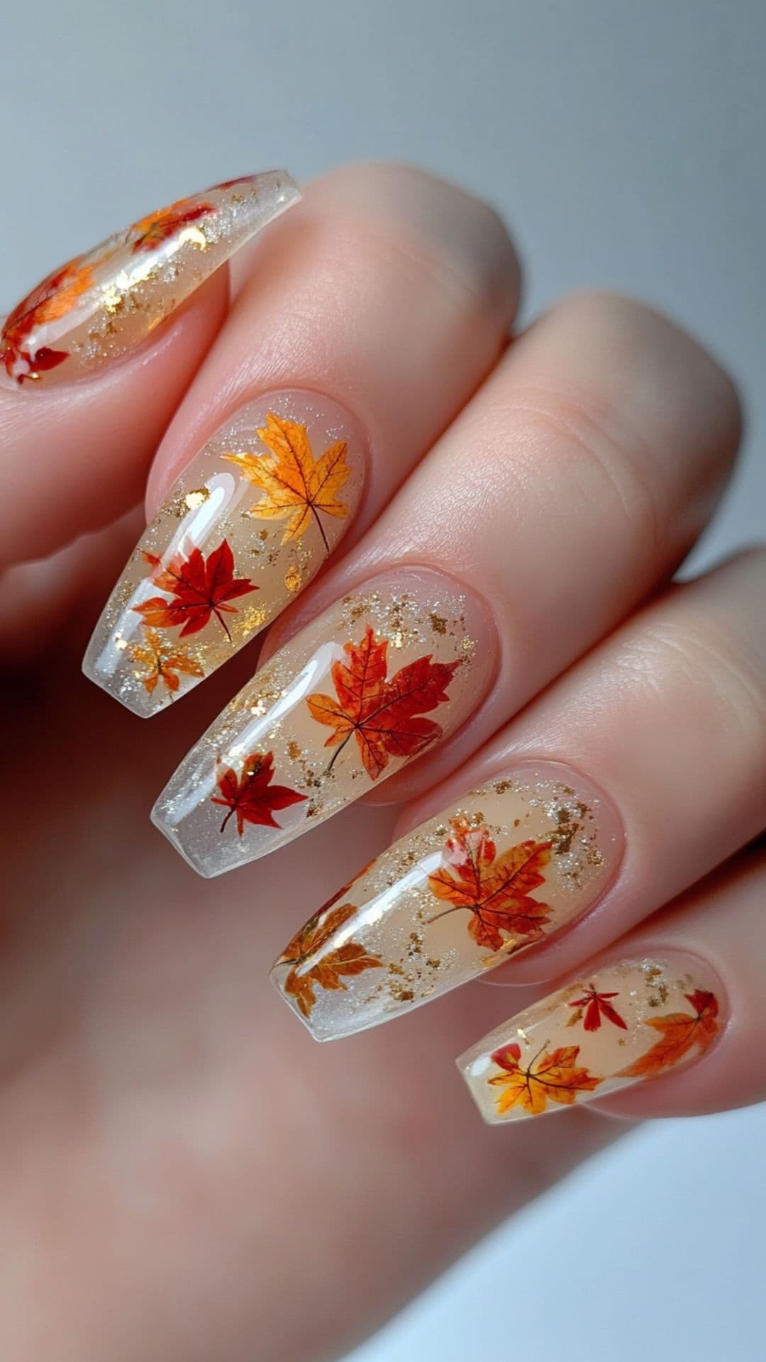 Woman's nails modelling Clear Nails with Encapsulated Leaves design.