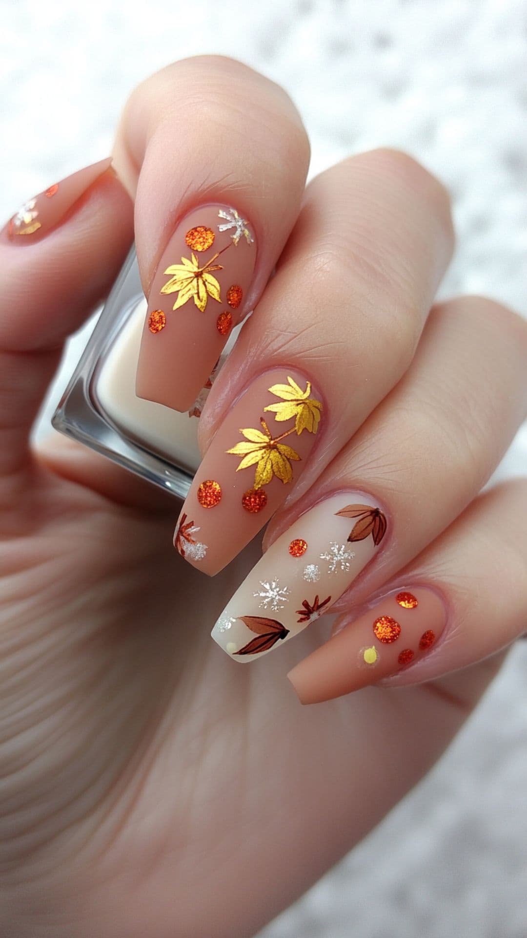 Woman's nails modelling Frosted Leaves on Pale Base design.