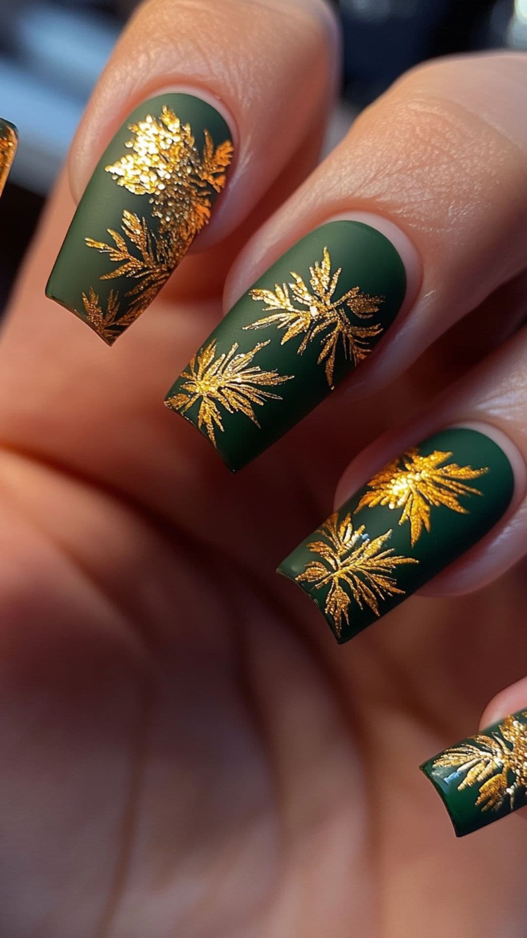 Woman's nails modelling Gold Foil Leaves on Deep Green Base design.