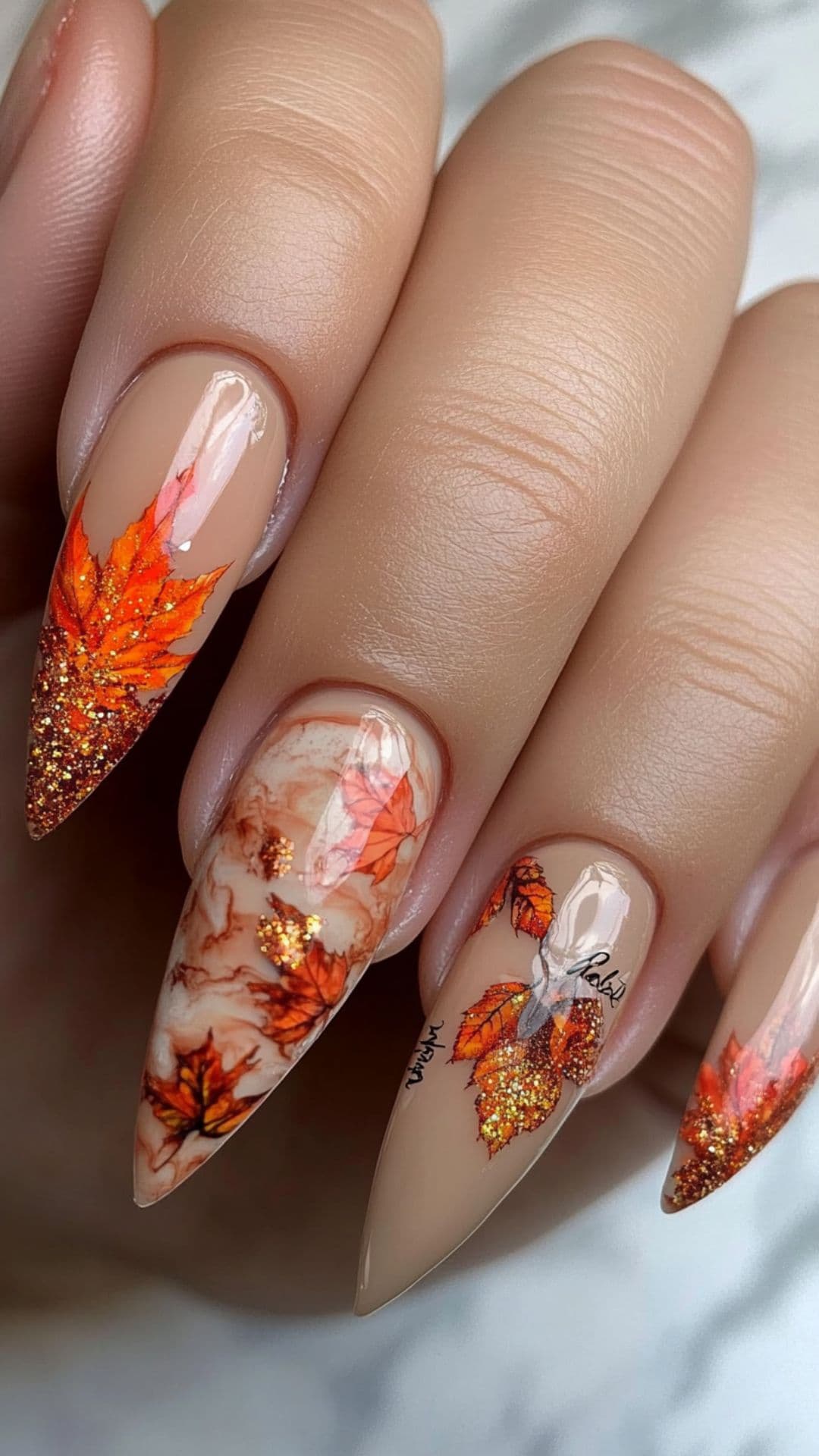 Woman's nails modelling Maple Leaves with Marble Nail Accent design.