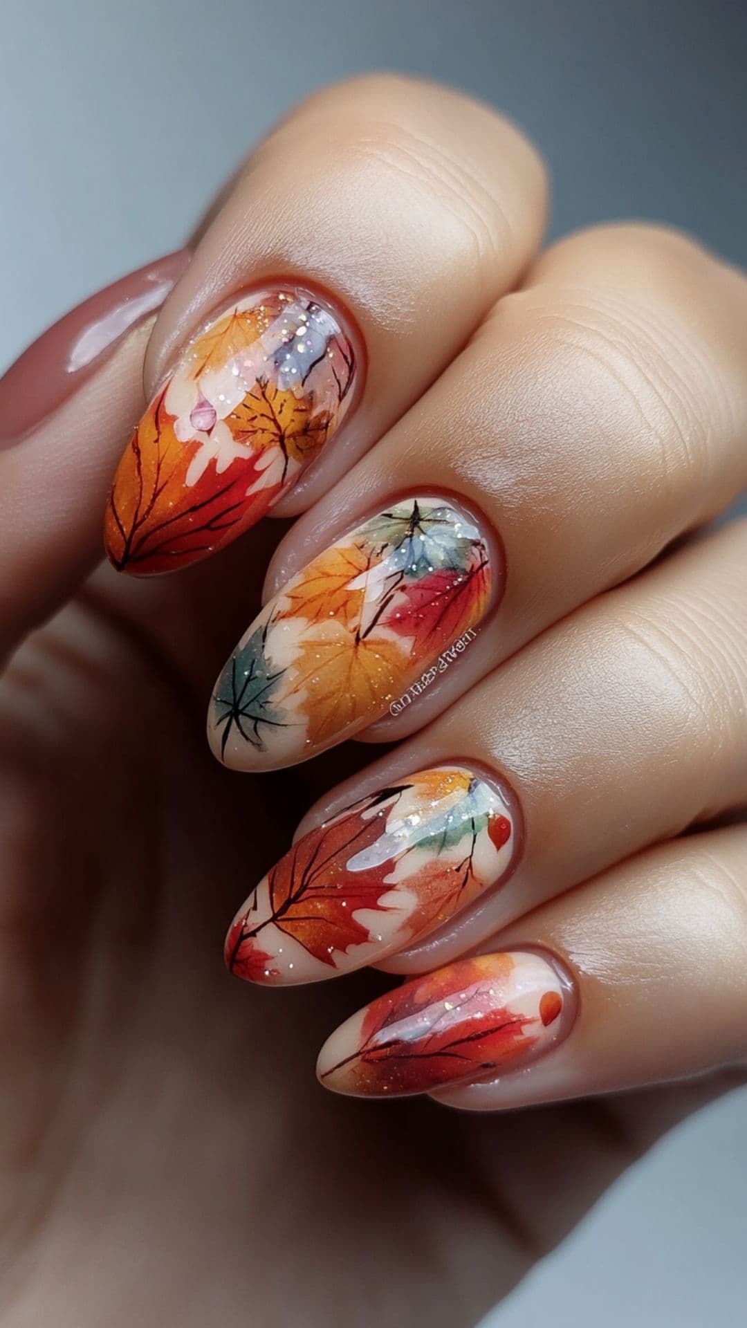 Woman's nails modelling Multicolor fall Leaves design on Neutral Base.