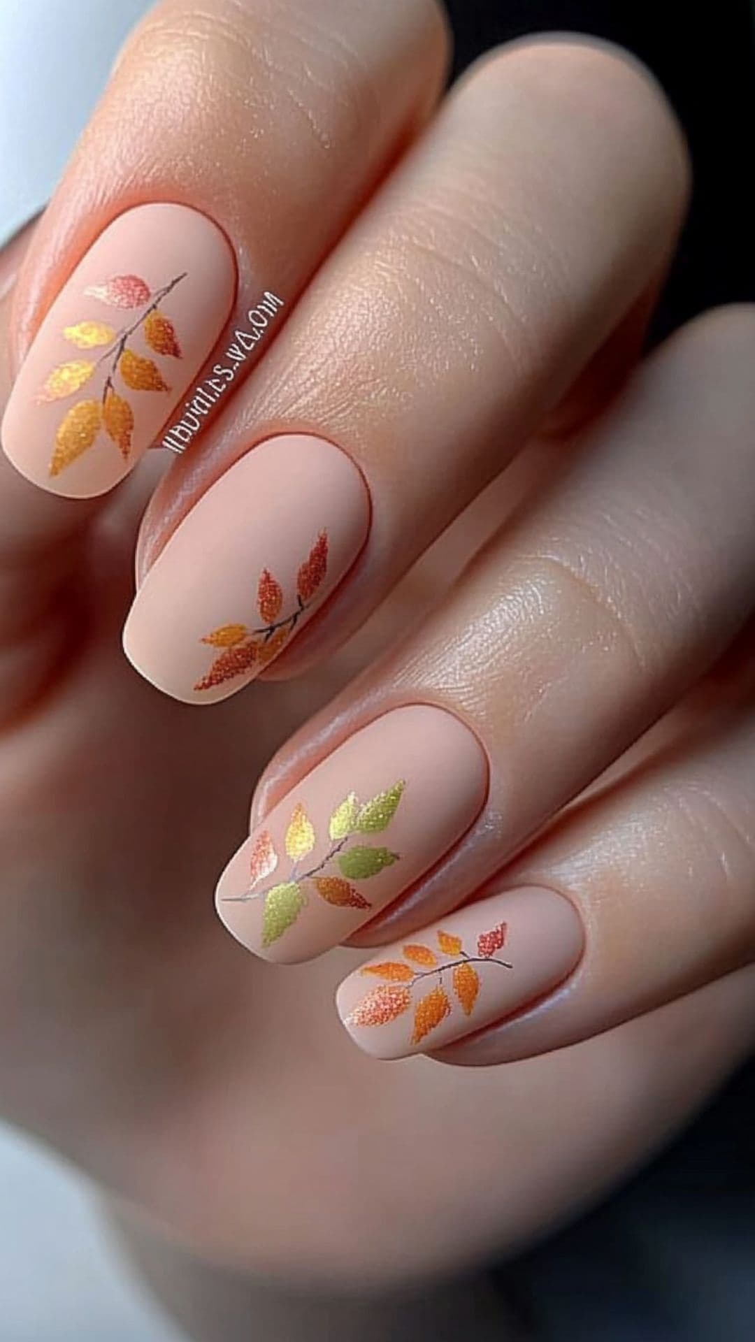 Woman's nails modelling Pastel Fall Leaves design.