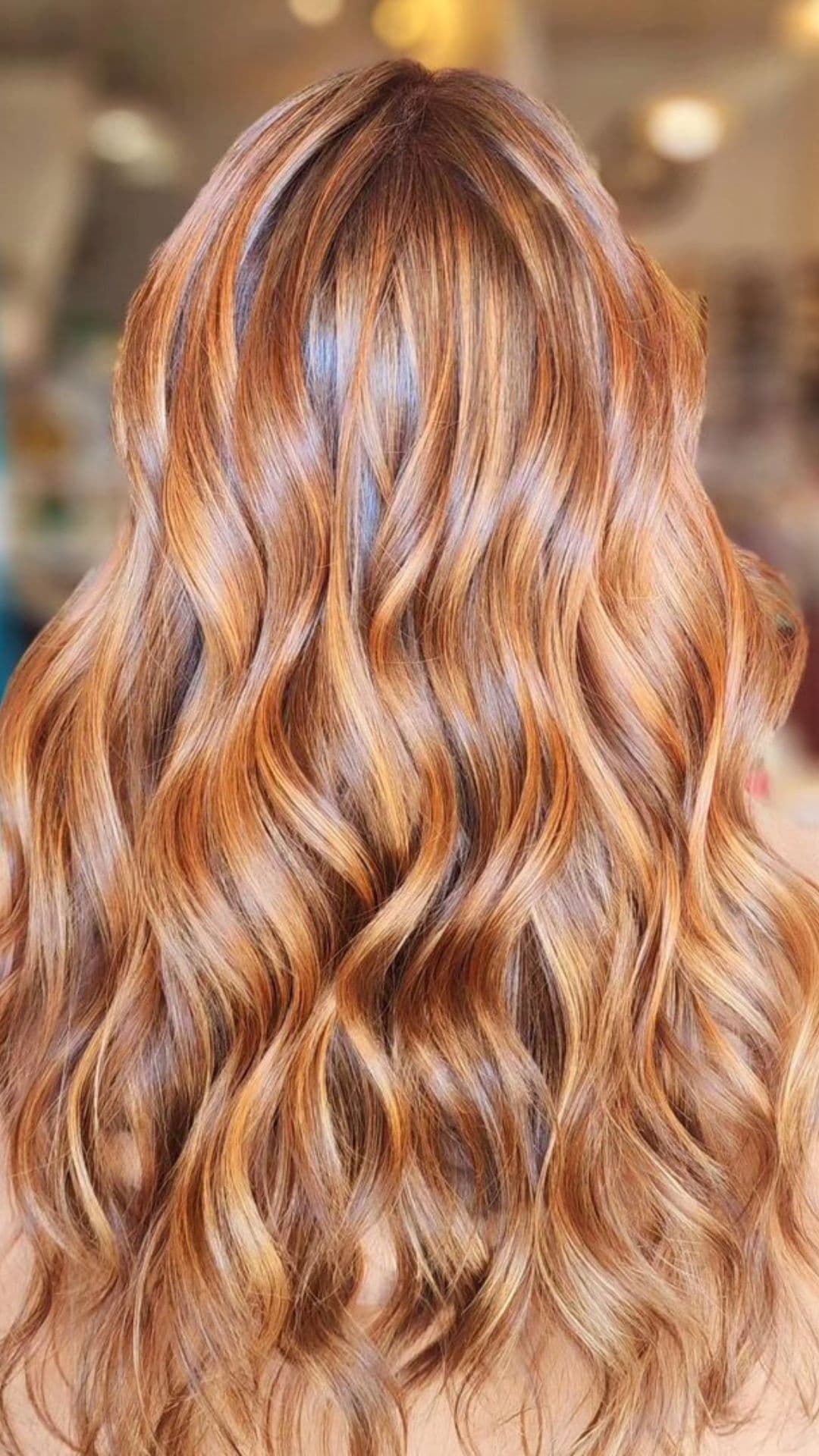 Close-up of wavy Copper and Gold hairstyle, showcasing vibrant and shiny curls.