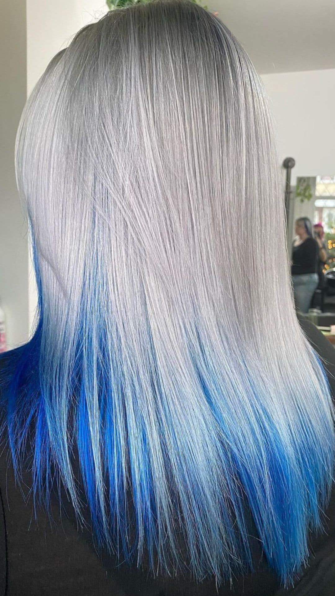 Person with a festive silver and blue dip dye hairstyle, showcasing a sleek look from the back.