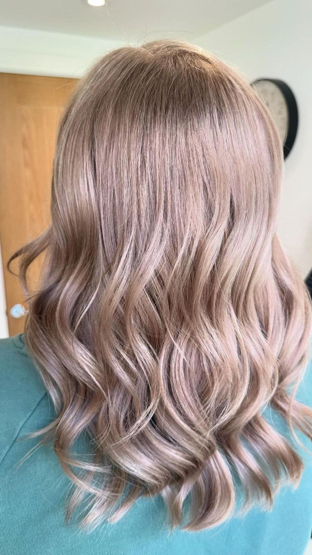 Woman with shoulder-length, wavy, Mushroom Blonde hair viewed from the back.