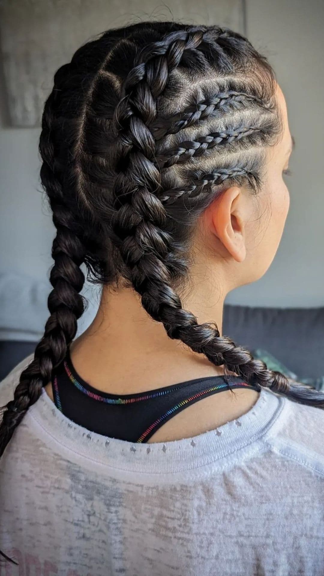 Person with Dutch braided pigtails hairstyle, wearing a light shirt. The braids are neatly woven from the front to the back of the head.