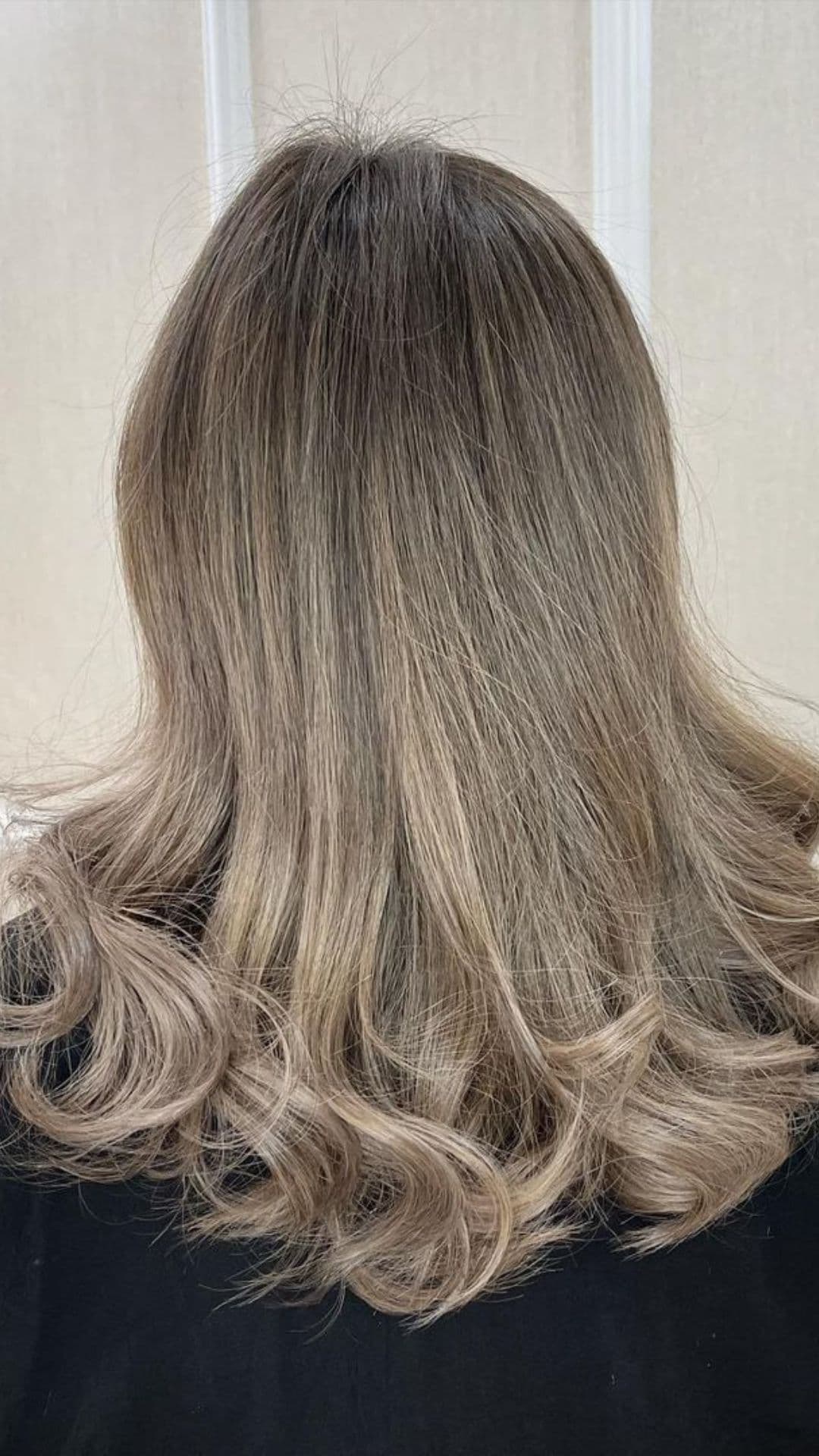 Back view of a person with Beige Brown Ombre hairstyle, featuring soft curls at the ends.