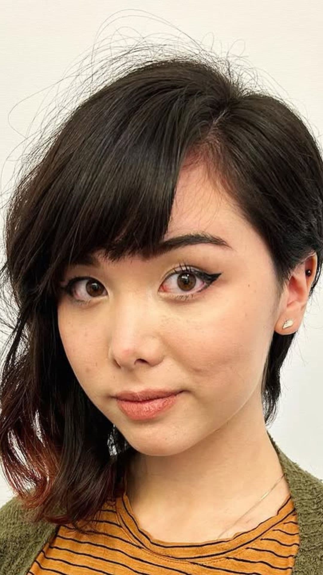 A woman with a round face modelling a Asymmetrical Bob with Side-Swept Bangs hairstyle.