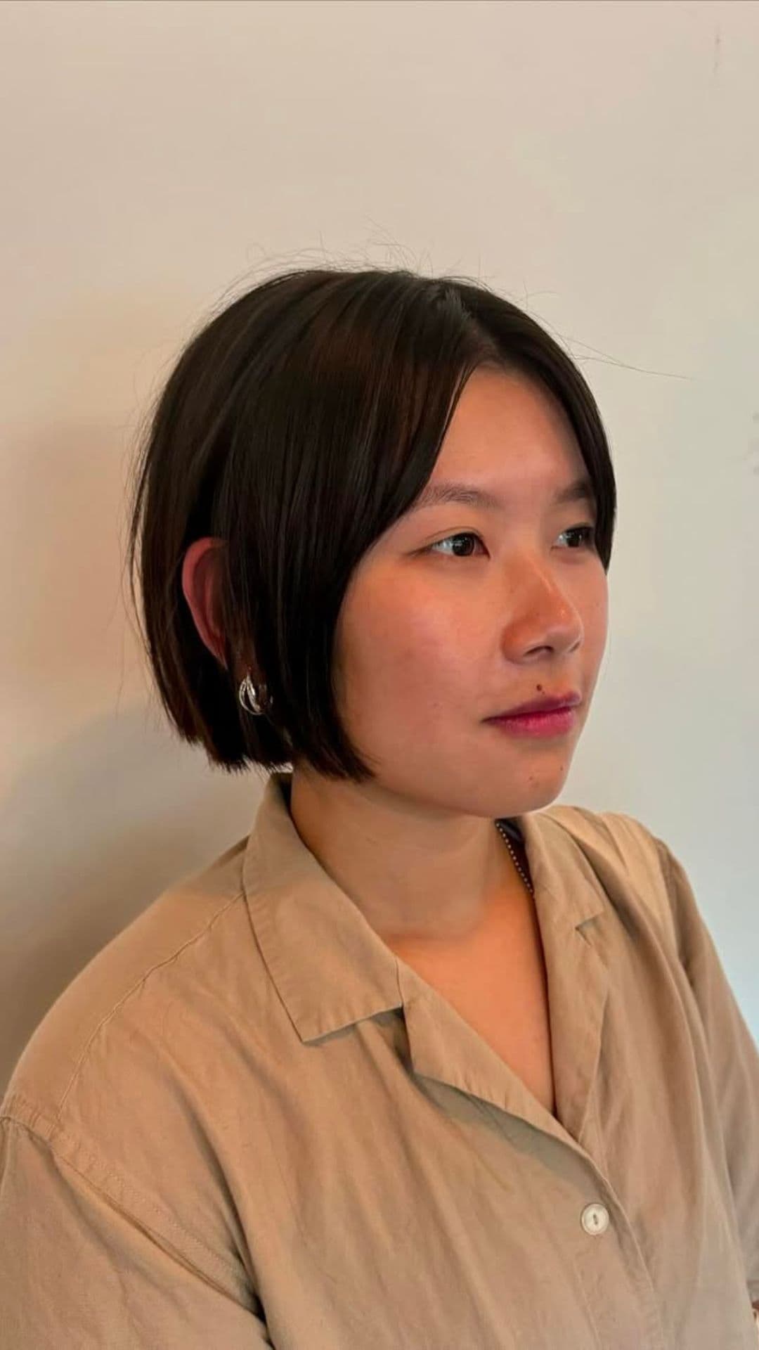 A woman with a round face modelling a Blunt Bob with Face-Framing Layers hairstyle.