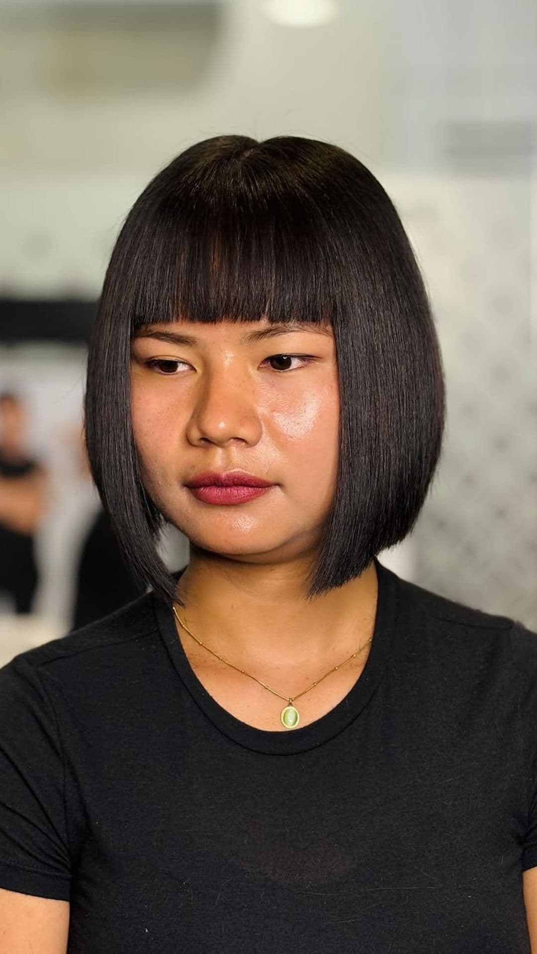 A woman with a round face modelling a Graduated Bob with Bangs hairstyle.