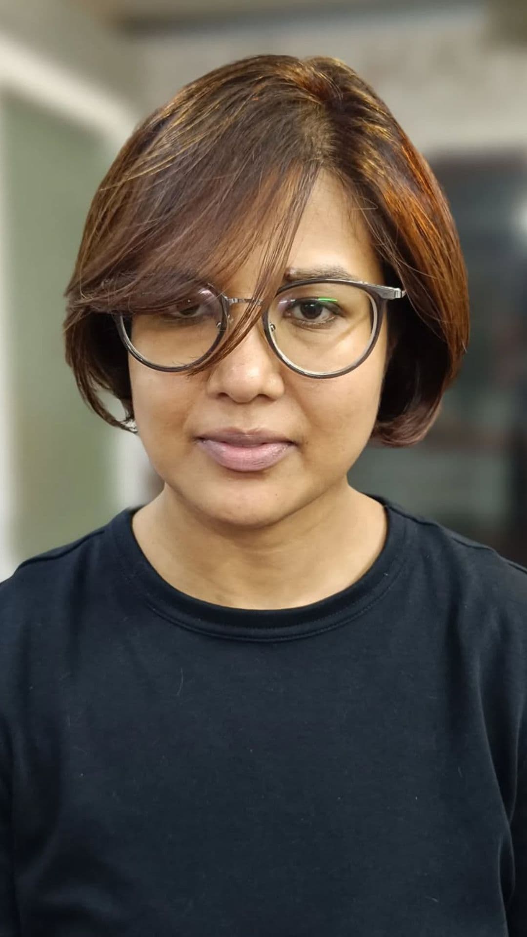 A woman with a round face modelling a Layered Bob with Side Bangs hairstyle.