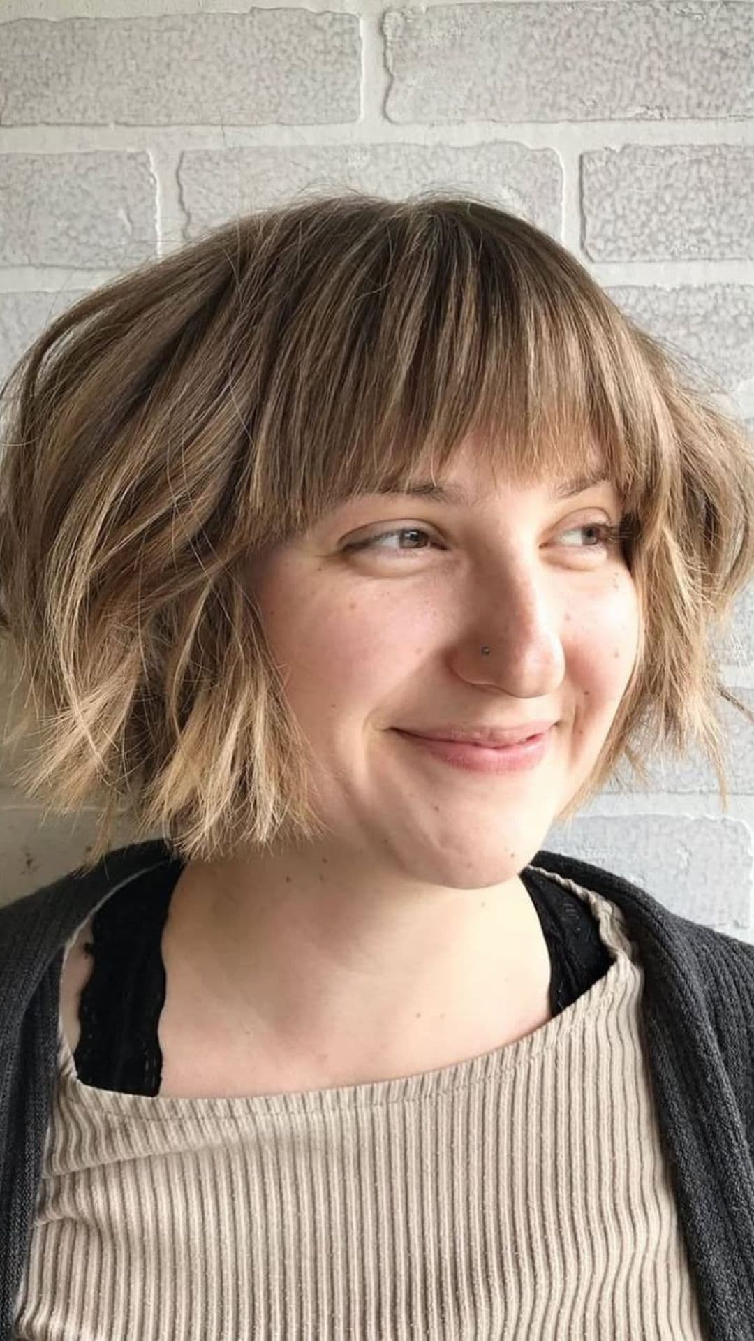 A woman with a round face modelling a Messy Bob with Blunt Bangs hairstyle.