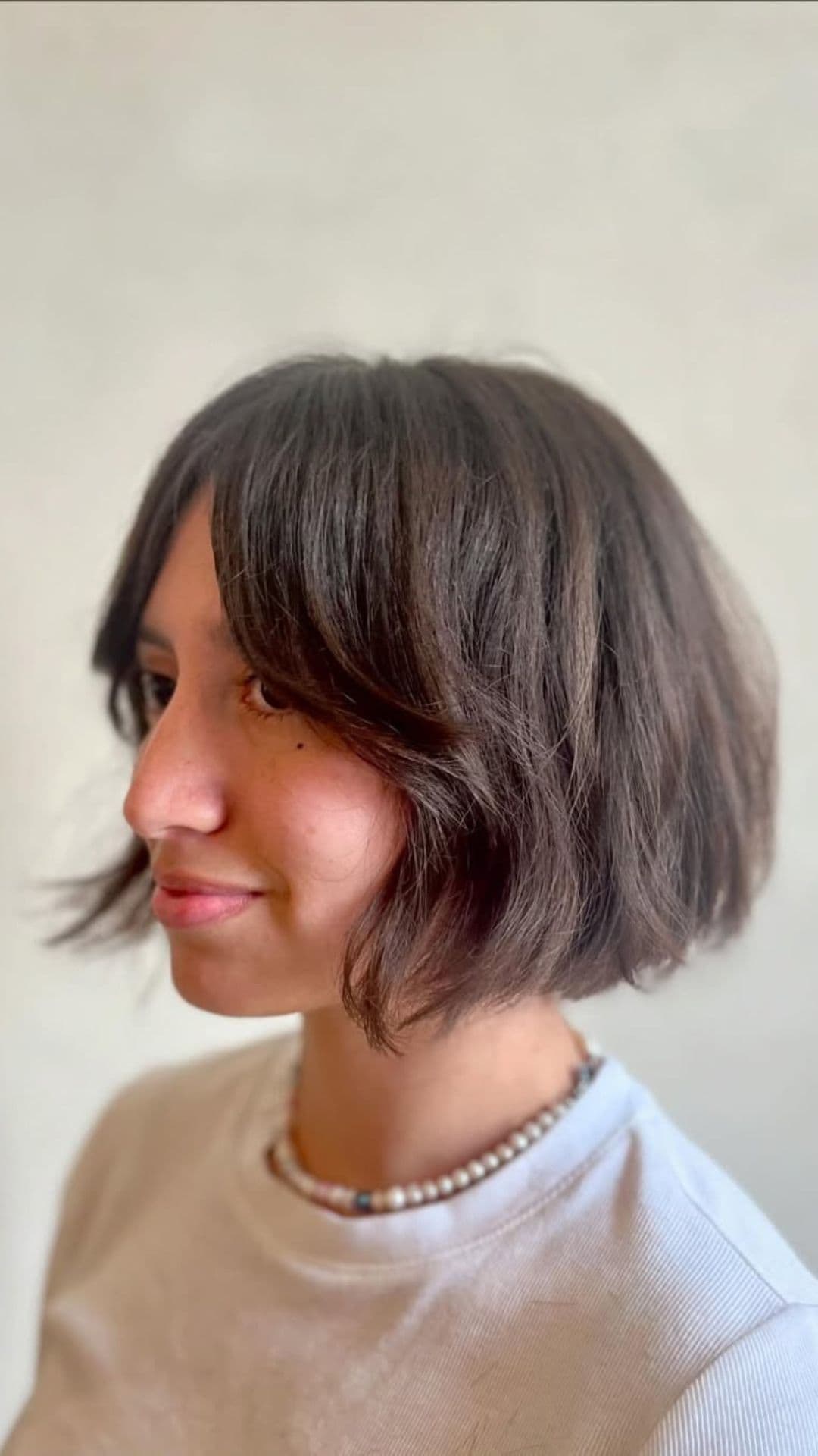 A woman with a round face modelling a Textured Wavy Bob hairstyle.